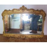 A gilt framed mirror, the shaped bevelled mirror plate enclosed by an arched frame with scroll and