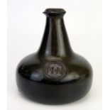 An 18th century green glass onion-shaped wine bottle, bears seal 'MN', 13cm tall,