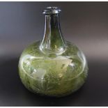 An early 18th century green glass wine bottle of onion shaped outline with scratched decoration of
