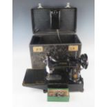 An early portable electric Singer sewing machine, model 222K1, in original box with accessories