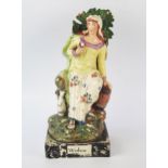 A Staffordshire pottery pearlware figure 'Widow' 26cm high. Chips to the foliage and loss of painted