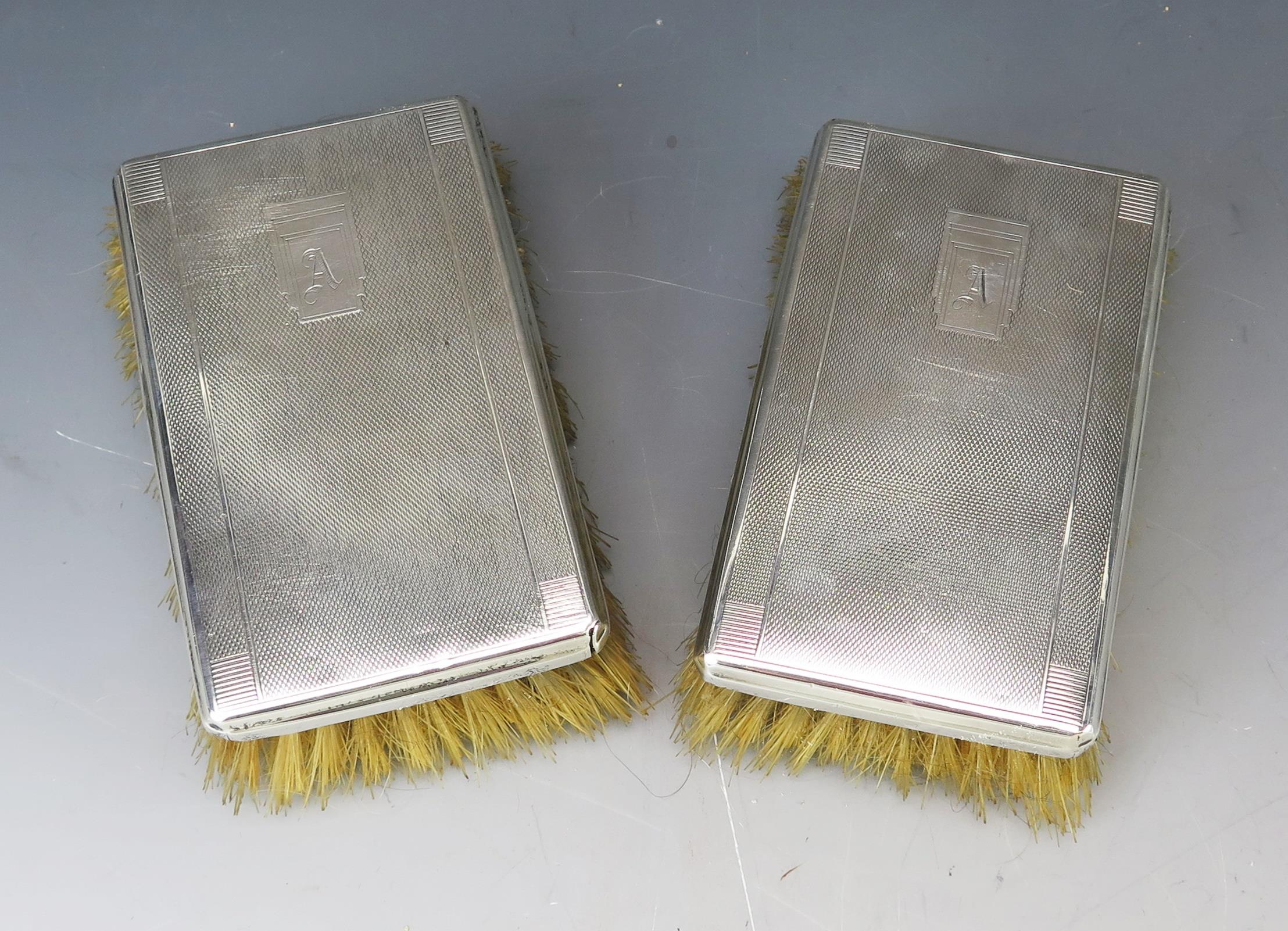 A pair of 20th century silver backed brushes, marks worn, initialled with engine turned decoration.