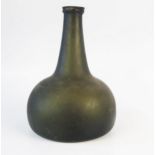 An early 18th century green glass wine bottle, of onion shape, with moulded neck ring, 19cm high.