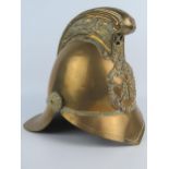 An all brass fireman's helmet, with dragon decorated comb, crossed axes and flaming torch badge,