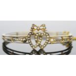 A Victorian 15ct Gold Hinged Bangle decorated with untested pearl set entwined hearts with bow over,