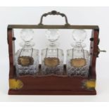 A mahogany and plate mounted three-decanter tantalus, of traditional design, with three clear