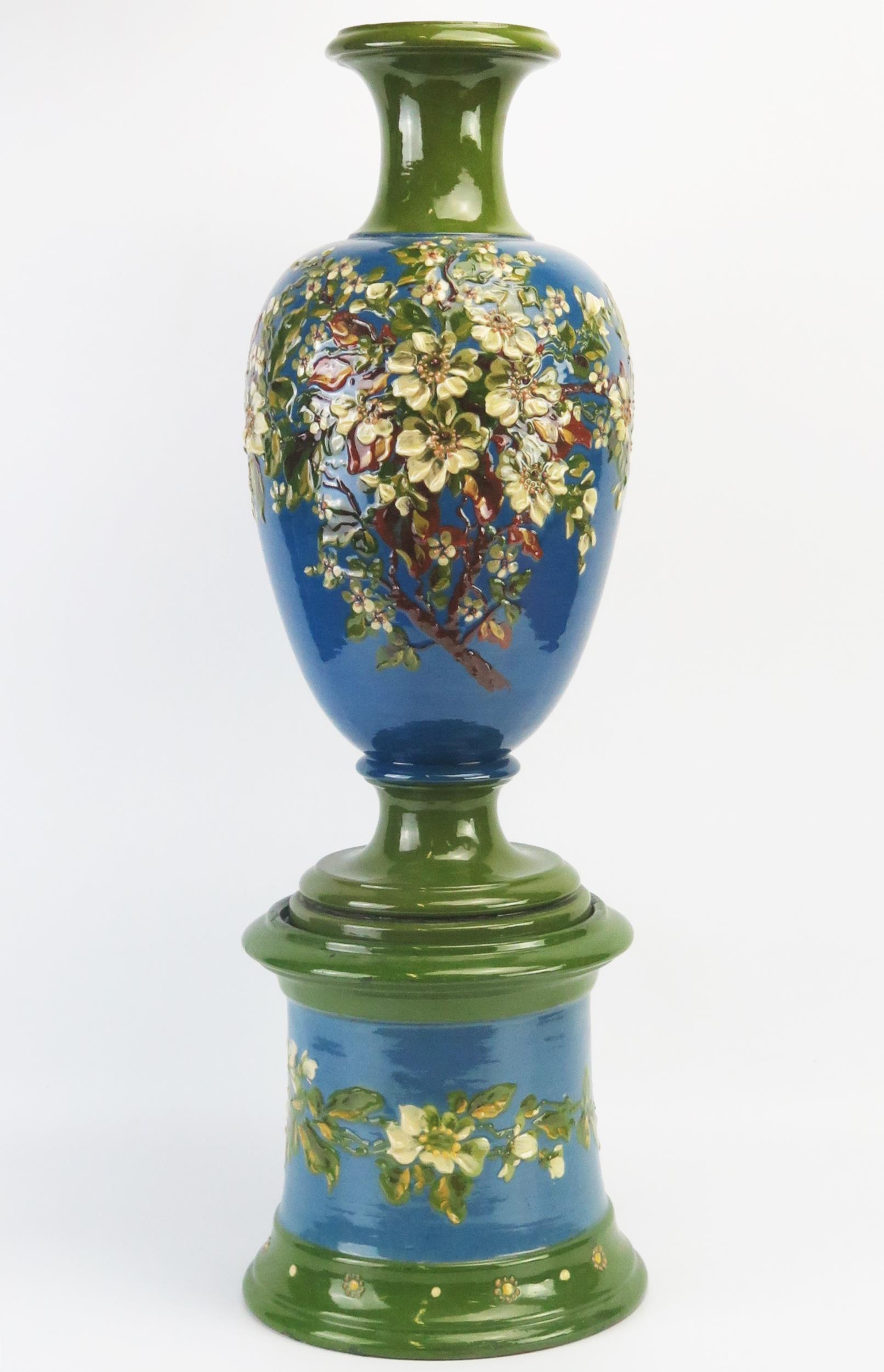 An Exeter Art Potteries barbotine vase and stand of ovoid form with low relief blossoming shrub