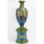 An Exeter Art Potteries barbotine vase and stand of ovoid form with low relief blossoming shrub