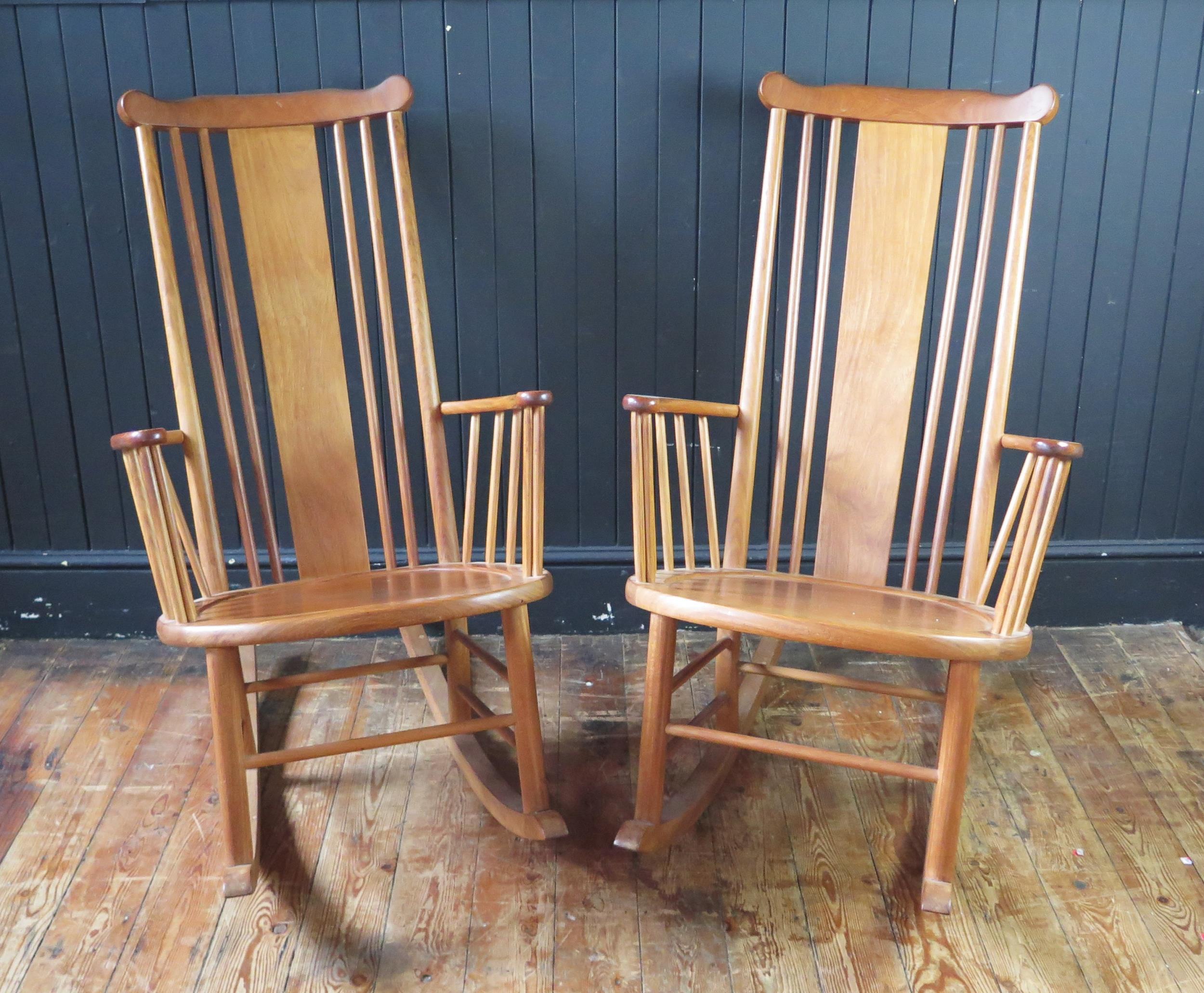 A pair of teak rocking chairs with solid central splat and spindle back with solid seat on rocker