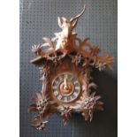 A Black Forest cuckoo clock, of traditional design the arched roof surmounted by a stags head,