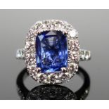 An 18ct White Gold, Sapphire and Diamond Cluster Ring, c. 10.2x8mm light blue stone, surrounded by