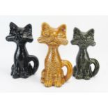 Three Dartmouth Pottery cat money boxes in black, dark green and brown glazes, each 22cm high.