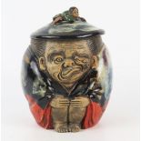A Japanese Sumida pottery character jar and cover, with seated grumpy looking figure, the domed