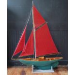 A painted fibreglass and wooden model of a single masted sailing ship, with green painted hull,