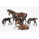 A Beswick model of a mare, with a lying foal, together with three Royal Doulton foals. (5)