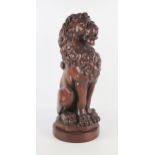 A carved oak model of a lion sejant, on a circular base, 44cm high.