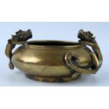 A Chinese bronze censer of squat circular form decorated with two dragons, holding the rim, bears