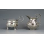 A Persian silver cream jug with repoussÃ© trailing foliate decoration and scroll handle, 9cm high,