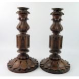 A pair of Victorian oak and bell metal candlesticks, with flared nozzles, foliate sconces on