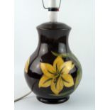 A Moorcroft pottery table lamp. the dark brown ovoid body decorated with yellow Bermuda lilies, 28cm