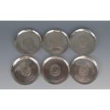 A set of six Middle Eastern silver coasters, of plain circular form with inset coins, 9cm