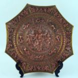 An Indian brass and copper octagonal plate, decorated in low relief with deities, animals and