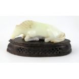 A Chinese carved jade figure of a recumbent horse, 9.5cm long, on a polished hardstone stand.