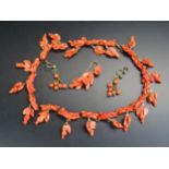 An Antique Carved Coral Necklace decorated with putti, knot and foliate drops, a single pendant
