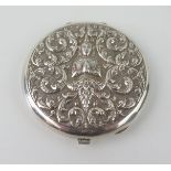 A sterling silver powder compact, stamped Sterling, with embossed Burmese deity decoration, with