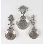 Three continental silver caddy and sifting spoons, all bear import marks, with repousse decorated