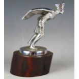A chrome plated car mascot in the form of an Egyptian winged god, mounted on a polishes wood base,