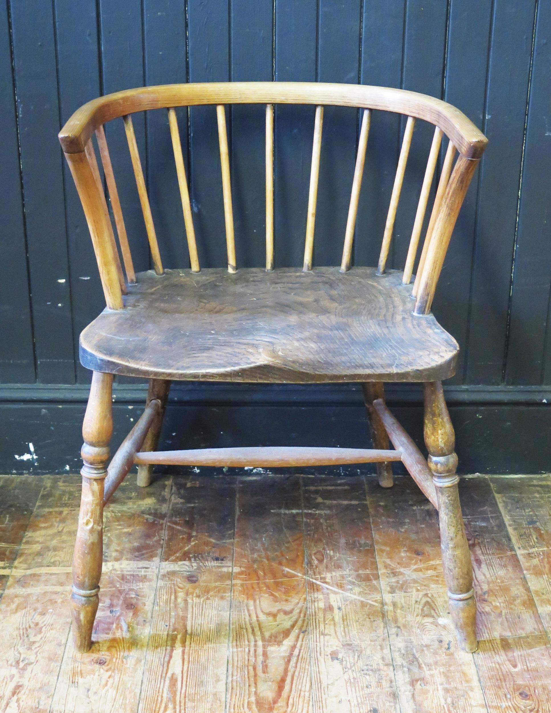 An elm elbow chair, having a stick back with curved top rail, solid seat on turned under framing.