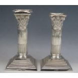 A pair of Edward VII silver Corinthian column candlesticks, with stop fluted columns on square