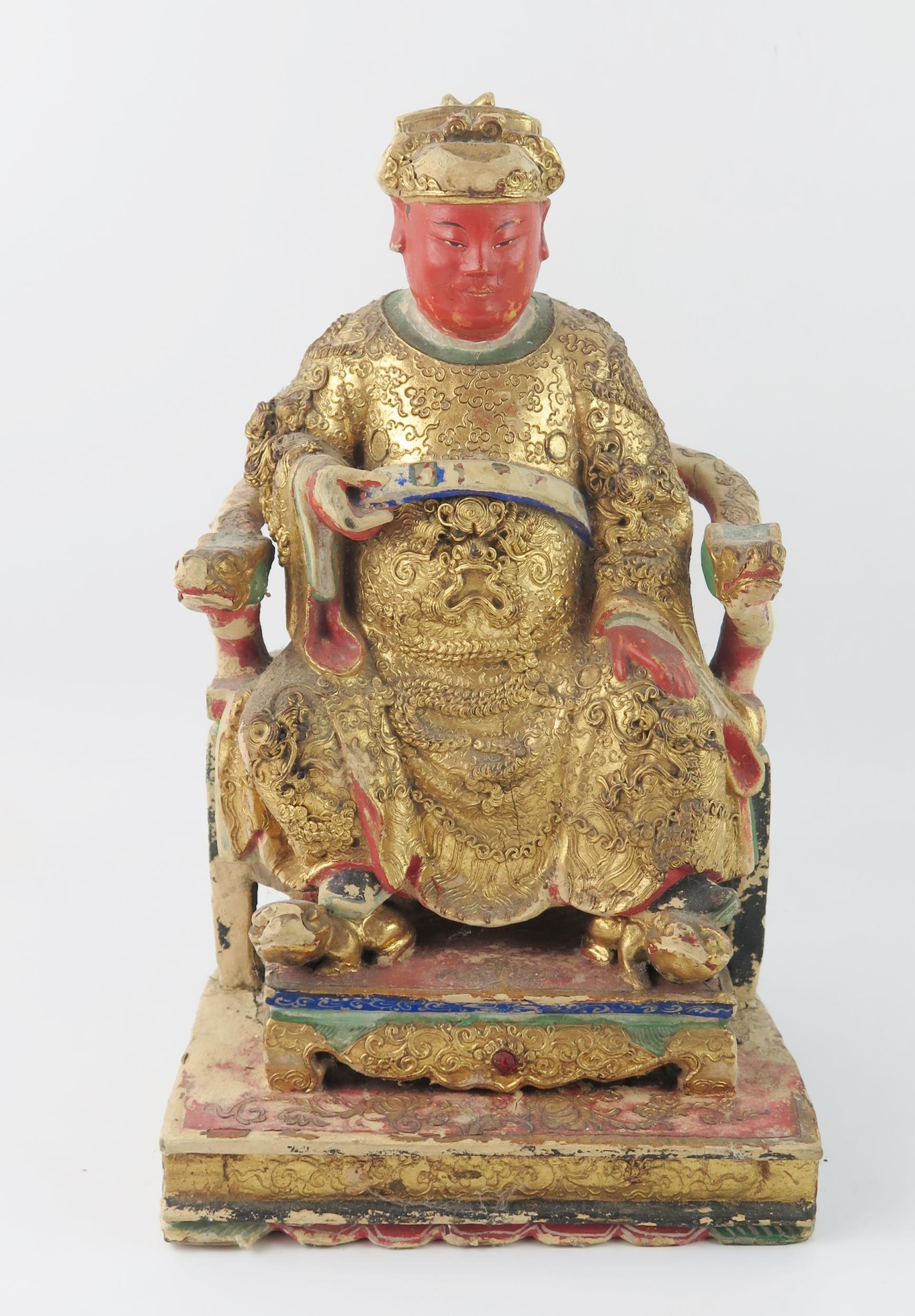 A late 19th century polychrome carved wooden figure of a seated emperor, with gilded decoration,