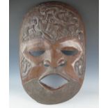 A large West African carved hardwood mask, of oval form, decorated with figures harvesting crops,