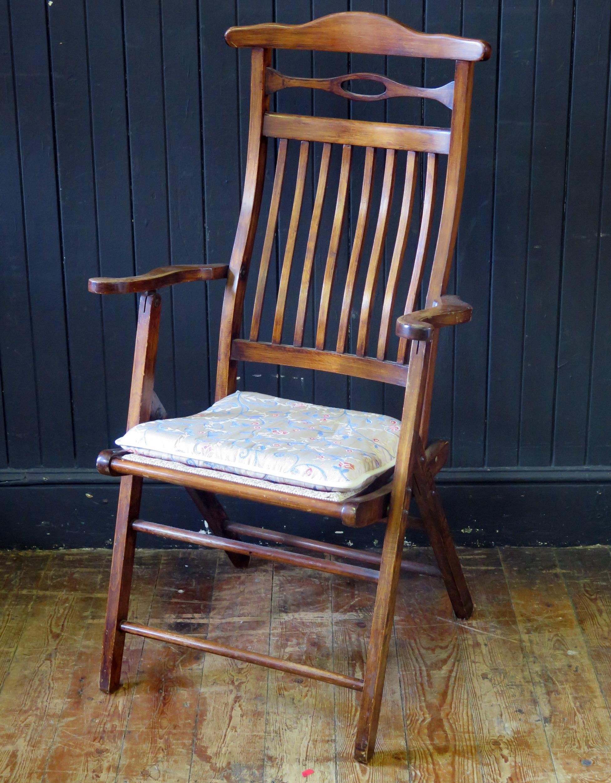 A stained beech folding elbow chair, with arched top rail and slat back, having a gross point wool