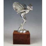 A chrome plated car mascot in the form of a winged nymph, mounted on a wood base, overall height