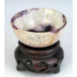A small Derbyshire blue john bowl, raised on a circular foot, on an associated Chinese wood stand,