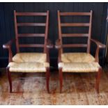 A pair of Brazilian mahogany ladderback elbow chairs, with sisal seats on swept legs.