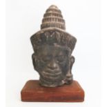 A Burmese reconstituted stone head of Buddha, mounted on a polished wood stand, overall height