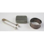 A silver napkin ring, a pair of silver sugar tongs, and a Cornish pewter castle top snuff box.