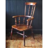 A late Georgian elm Windsor style elbow chair, with high comb back, solid seat on turned legs united