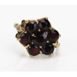 A 9ct Gold and Garnet Cluster Ring set with seven c. 5.8-4.2mm stones, 15mm head, hallmarked, size