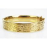 A 9ct Gold Hinged Bangle with chased scrolling decoration, hallmarked, 19.8g