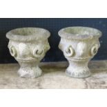 A pair of reconstituted stone garden urns, of campana form with lion mask decoration, on circular