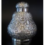 A white metal tea caddy and cover, unmarked of baluster form, with embossed foliate and flowerhead