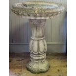 A reconstituted stone bird bath, the circular bath with moulded rim raised on a waisted and