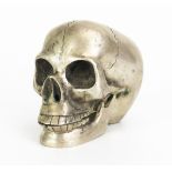 A metal paperweight in the form of a skull with hinged jaw, 12cm long.