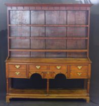 An 18th century oak dresser, with shelved and planked superstructure, the base with shaped apron