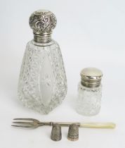 A clear glass and silver mounted scent bottle, a smaller silver topped jar, two thimbles and an